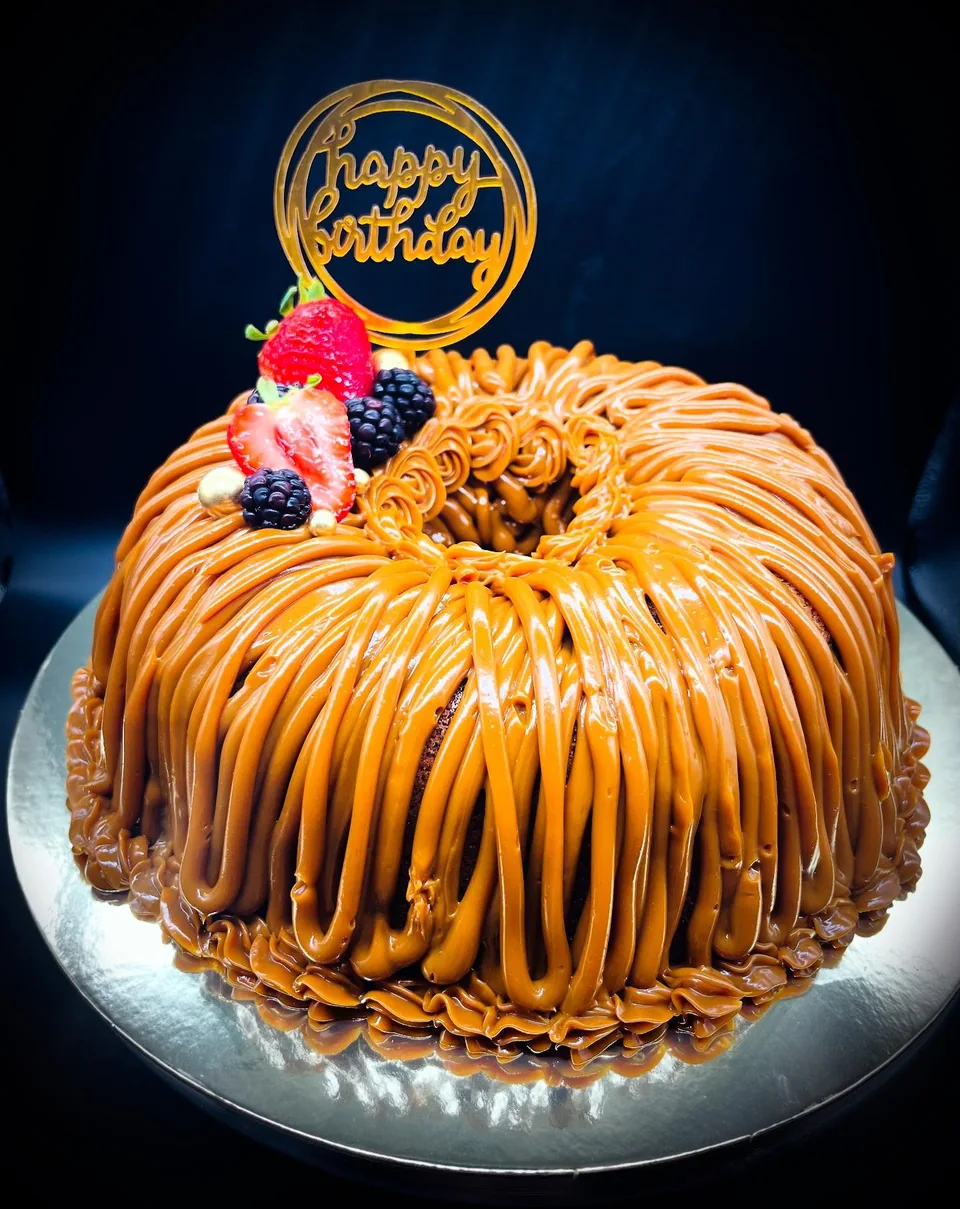 Bundt cake cubierto de dulce de leche con frutas y topper dorado