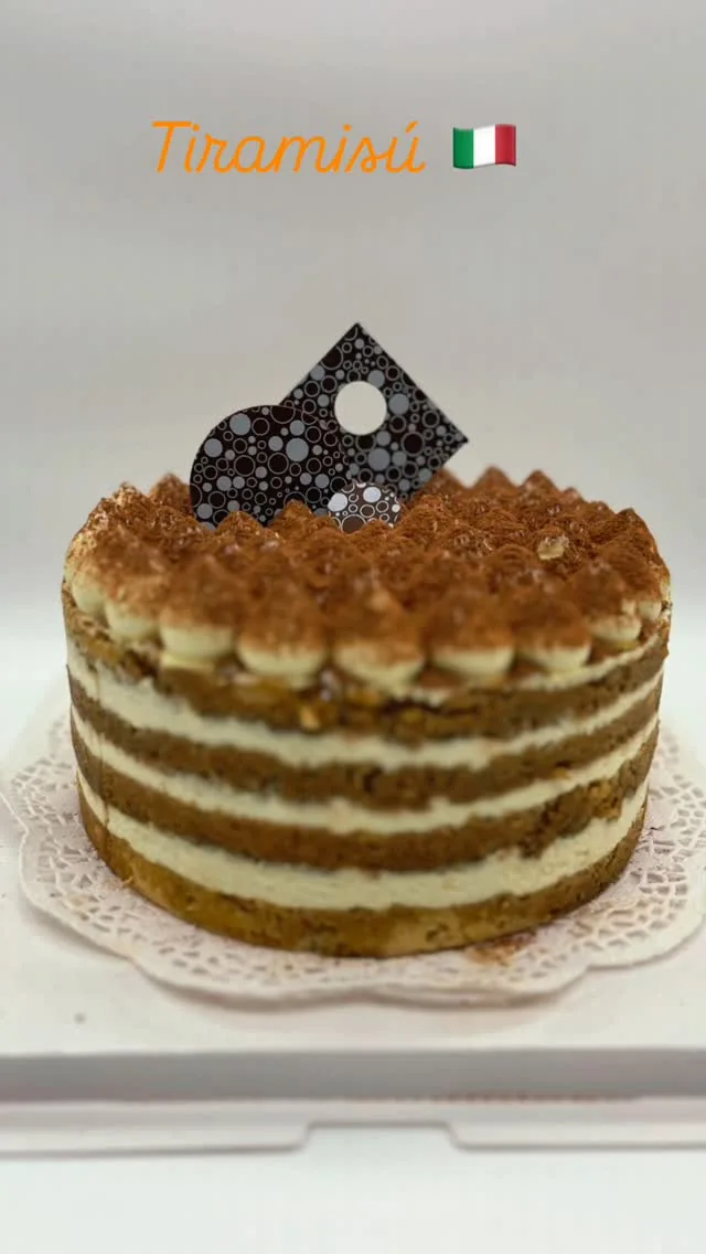 Tiramisú redondo con capas de crema, cacao y decoración de chocolate